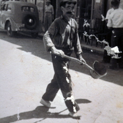 L'empleat municipal Joaquim Corones regant la plaça amb l'eina d'aquells temps en un dia de festa assenyelada.