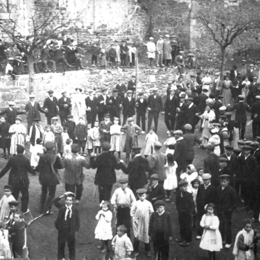 Una festa de Sant Antoni a principis del segle XX amb la tradicional ballada de sardanes a la plaça. Com a nota característica, la vestimenta de les dones i la mainada i els homes tots amb gorra.

El lloc on toca la cobla és l'antic cementiri que encara no s'havia acabat d'adecuar tal com és actualment.