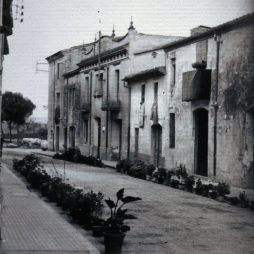 Detall del carrer dels Dolors per la festa de Corpus. Es pot observar com en cada casa a més de poser en els balcons i finestres les millors vànoves o damascos que tenien , també posaven a la vorera davant la porta, tots els testos amb flors de què disposaven. Les cases que es veuen en aquesta foto són avui totalment reformades i compensen els comerços de Benito Pons, carnseria, Can Grill supermercat, Can Mero, moble i la M Rosa robes i merceria.