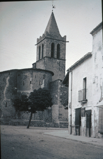Detall de la plaça de l'Església abans de ser restaurada la casa Can Júria.

A la foto encara hi ha una de les antigues escàcies que foren substituïdes al cap de poc temps per les actuals (2001) arces i moreres.