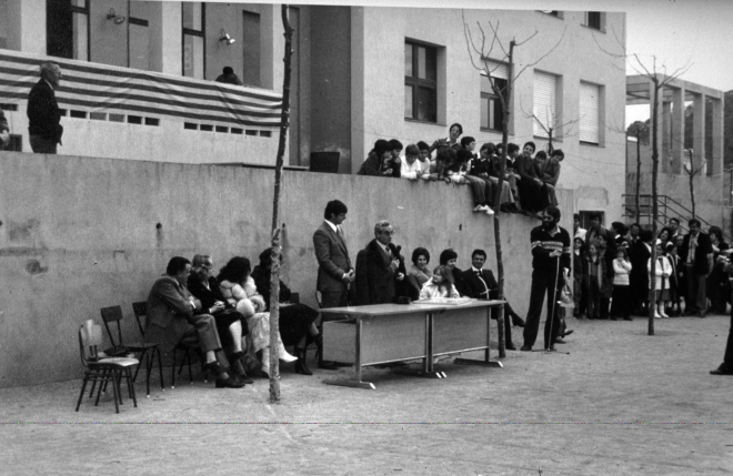 Acte d'homenatge al mestre Sr. Lluís Serra Domingo amb motiu de la seva jubilació al pati del col·legi Sant Jordi de Maçanet. 
Al costat de l'homenatjat hi ha el Sr. Serra que està dirigint la paraula als assistents a l'acte, es pot observar a l'alcalde Sr. Antoni Planas.