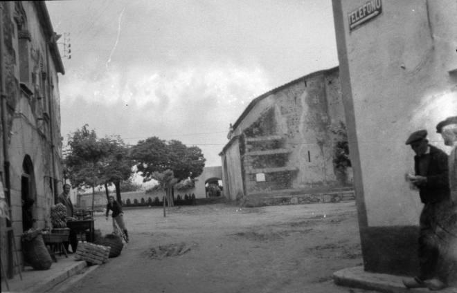 Vista de la plaça de l'Església l'any 1945. Com es pot observar per aquella època no corria ni un sol cotxe. Era el temps dels gasógens per manera de gasolina; com tampoc hi havia neumàtics per les rodes dels pocs cotxes que existien. A la dreta en Josep Reixach de nom Josep Orench i a l'esquerra Marti Masjoan de Can Jordi.