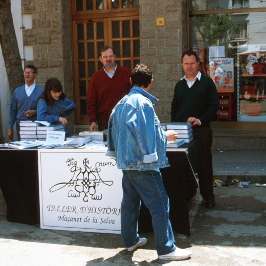 En Lluís Soler i en Narcís Vilella venent llibres de la Nostra Vila en el dia de la fira artesanal.