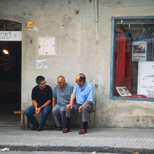 En Joaquim Bosch i Font, en Josep Vila, en Martí Rosell asseguts al davant de Ca l'Ubà vell a la plaça de l'Església on hi havia instal·lada l'exposició de fotografies que el Taller d'història ofereix cada any per la Festa Major.