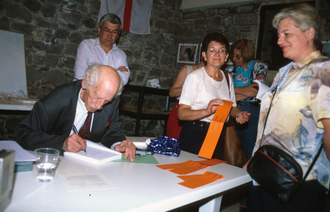 El Sr. Manel Anglada signant uns papers en presència de Juli Campeny, Assumpció Artigas i Susana Clarió