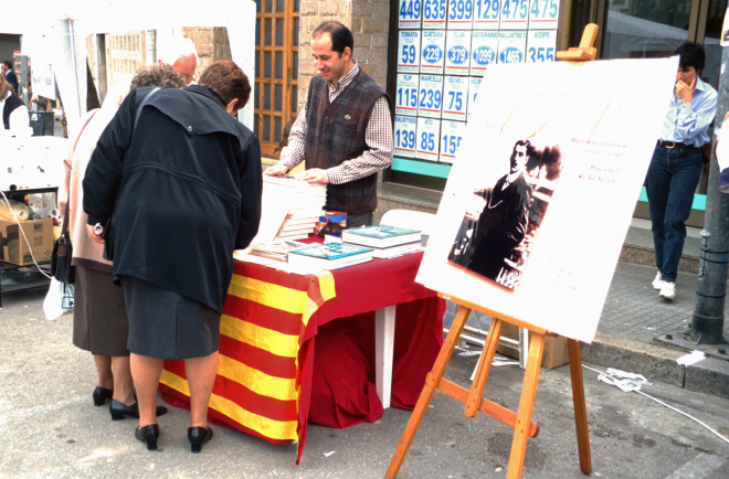 En Josep Costa en el lloc de venda de llibres del taller d'Història, el dia de la Fira artesanal de Maçanet.