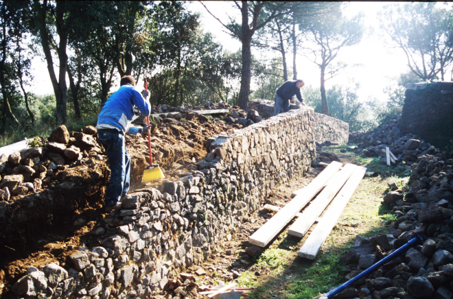 El paleta Joan Machado i el seu ajudant en els treballs de reconstrucció dels murs del fossar del castell de Torcafelló