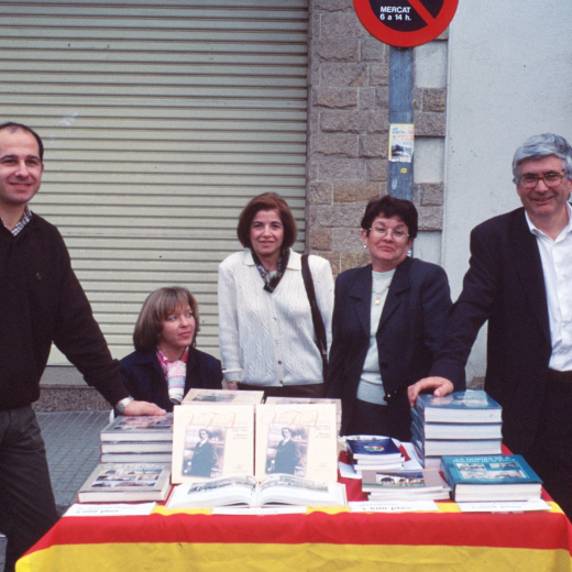 Parada de venda de llibres del taller d'història a la fira artesanal.

D'esquerra a dreta: Josep Costa, asseguda Glòria Caballer, Angela Artigas, Assumpció Artigas, i el Cap de Colla i President de l'entitat Juli Campeny. Estan molt contents perquè fa bon temps i la venda va bé.