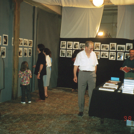 Martí Rossell, Josep Costa, i Narcís Munsó del taller d'història cuiden de la venda de llibres mentre la gent visita l'exposició de fotografies de casaments antics