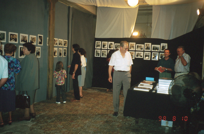 Martí Rossell, Josep Costa, i Narcís Munsó del taller d'història cuiden de la venda de llibres mentre la gent visita l'exposició de fotografies de casaments antics