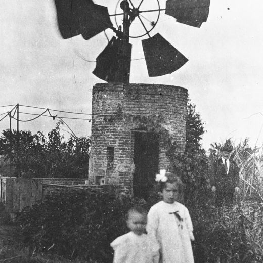 Els germans Joan i Aurelia Lluís Tomàs i al fons el seu pare en Josep Lluís, junt al molí de vent que per aquells temps hi havia a la masia Can Cartellà Nou, casa situada al peu de la carretera Nacional II