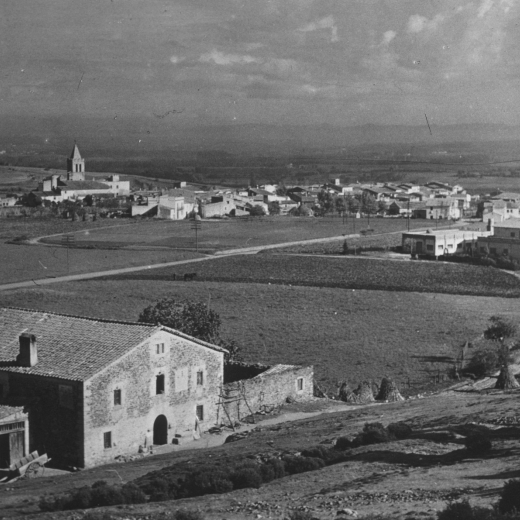 Vista parcial de la vila de Maçanet i en primer terme l'antiquíssima masia Can Roura.
