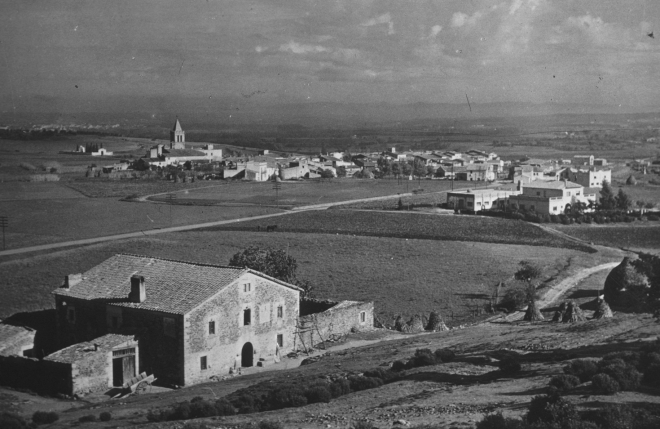 Vista parcial de la vila de Maçanet i en primer terme l'antiquíssima masia Can Roura.