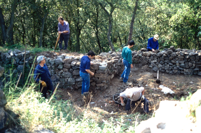 La gent del Taller d'Història treballant en la neteja i desenrunament dels fossars que envolten el recinte, treball previ a la reconstrucció dels murs. En Xavier Vergès, en Josep Panosa, en Francesc Guinart, en Martí Tomàs, en Jordi Vergès, i el que porta barret és en Josep Reyner.