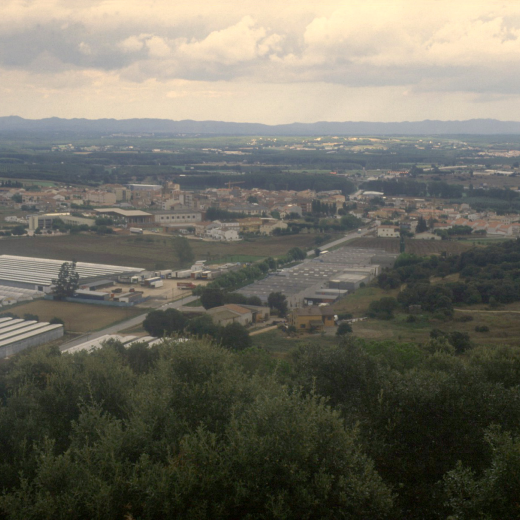 Vista general de la vila de Maçanet amb les naus industrials de can Roura i els hivernacles d'en Toni Falló.