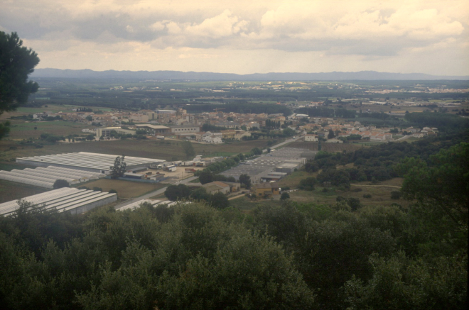 Vista general de la vila de Maçanet amb les naus industrials de can Roura i els hivernacles d'en Toni Falló.