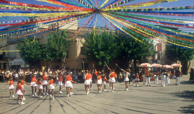 Detall de la plaça de l'església al dia de festa major, amb l'exhibició de les majorets de Maçanet. La plaça està emplenada.