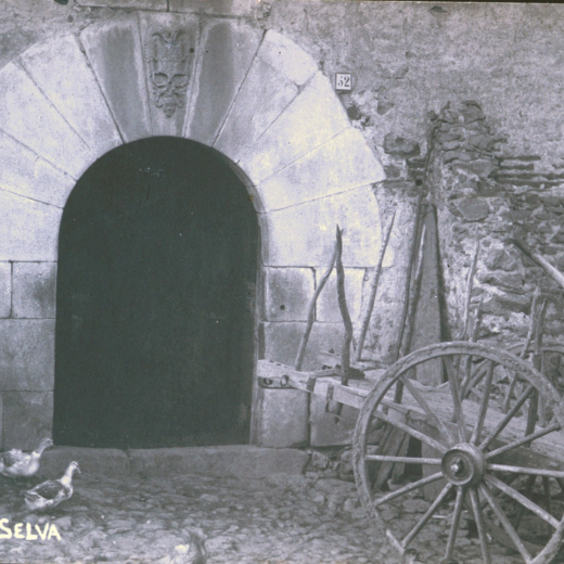 Portal d'entrada de la masia Can Reixach amb una antiga carreta i una colla d'ànecs.
