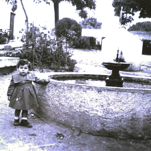 La nena Assumpció Bagué i Pujol junt al surtidor, avui desaparegut a la plaça de l'Església.