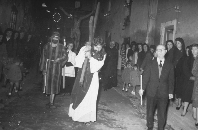 Processó del Divendres Sant a Maçanet. Pas de Jesús arrossegant la Creu i en Miquel Coll, un dels organitzadors de la processó, amb un ciri passant pel carrer Migdia.