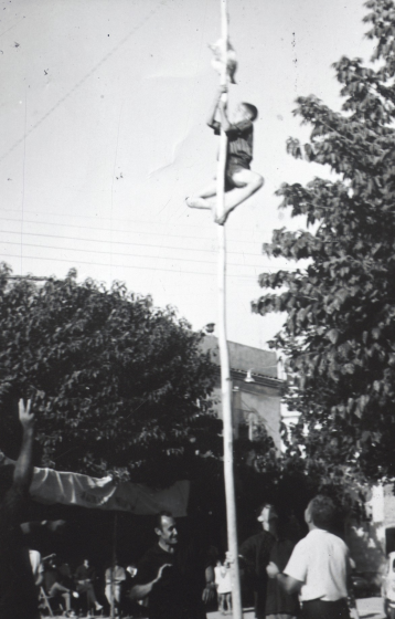 Festa Major del 1960. Jocs de cucanya a la plaça de l'Església. A peu del pal s'hi pot veure a Josep Roura, un dels organitzadors dels jocs.