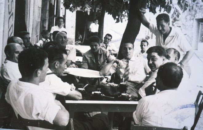 Tertúlia de jovent del poble davant el bar Can Júria un diumenge d'estiu.

Josep Soms, Josep Viader, l'avi Jordi, Manel Reyner, Francisco Baños, Anna Gelmà i el seu fill Alfonso Llinas, Pere Caballé, Ismael Viader i a la porta Ramon Bagué