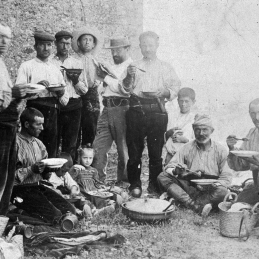 Una colla de treballadors d'en Trinxeria en ple dinar mentre l'amo vigila i llegeix el diari.